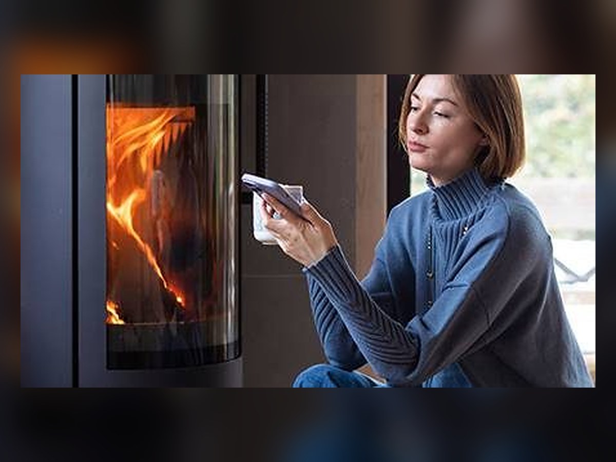 Déclarer un poêle à bois à son assurance : propriétaire consultant son contrat sur son téléphone devant son poêle